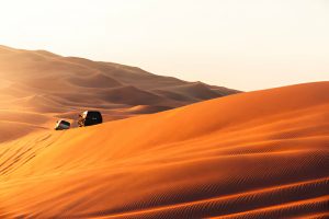 Travelers on a Morocco desert tour walking across golden Sahara sand dunes